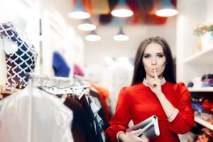 Mulher em loja de roupas pedindo silencio, como se para ser um cliente oculto você precisasse agir com cautela