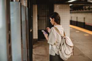 uma mulher jovem com um mochila branca nas costas esperando o metro